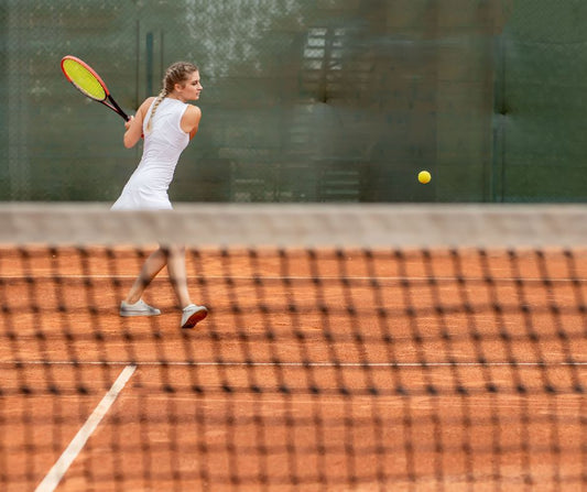 Woman hitting tennis ball on a clay court